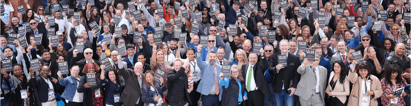 A large group of entrepreneurs holding the D.R.I.V.E. book.